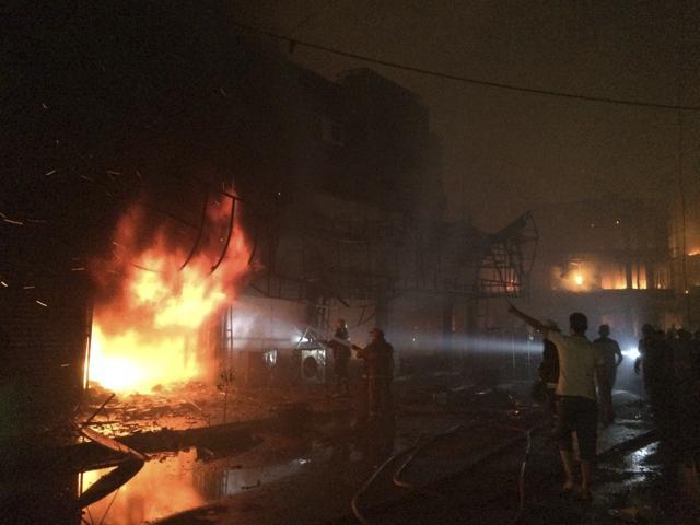 Iraqi firefighters extinguish a fire as civilians gather after a car bomb. (AP Photo) Iraqi firefighters extinguish a fire as civilians gather after a car bomb. (AP Photo)