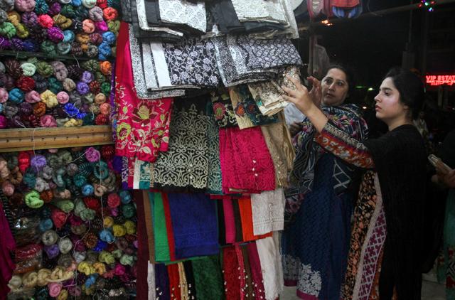 Pakistani women buy matching shawl with their new clothes for the upcoming Eid al-Fitr holiday to mark the end of the holy fasting month of Ramadan in Karachi, Pakistan, Sunday, July 3, 2016.  (AP) 