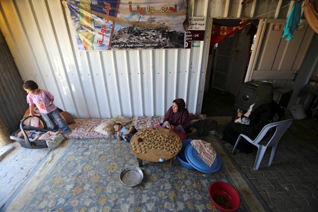 A Palestinian family, whose house was destroyed during 2014 war, make traditional cakes inside their makeshift shelter, ahead of Eid-al-Fitr celebrations in Khan Younis in the southern Gaza Strip July 3, 2016.  (REUTERS) 