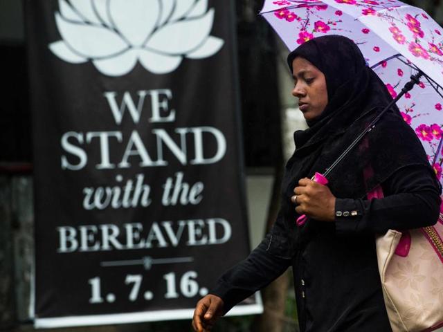 A Bangladeshi woman walks past a banner that reads "We stand with the bereaved" in a street near the upscale restaurant, the site of a bloody siege in Dhaka.(AFP)