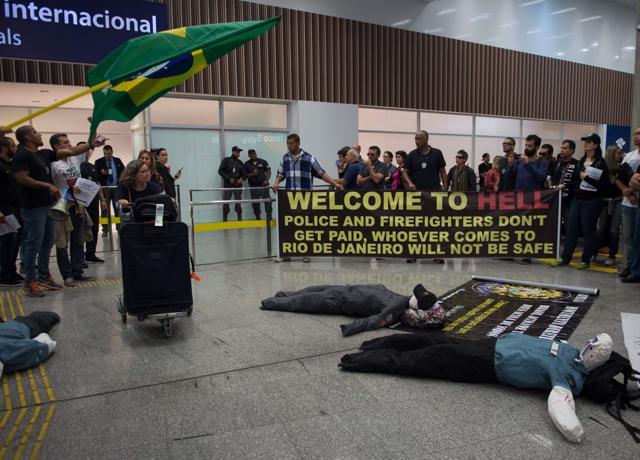 Police officers and firemen welcome passengers with a banner reading "Welcome to Hell" as the protest against the government for delay in their salary payments at Tom Jobim International Airport in Rio de Janeiro, Brazil. (AFP Photo) Police officers and firemen welcome passengers with a banner reading "Welcome to Hell" as the protest against the government for delay in their salary payments at Tom Jobim International Airport in Rio de Janeiro, Brazil. (AFP Photo)
