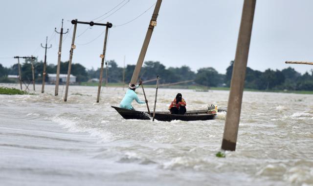 Indian villagers paddle a boat along a submerged road in the flood-affected Ashighar village in Assam on Tuesday. (AFP) Indian villagers paddle a boat along a submerged road in the flood-affected Ashighar village in Assam on Tuesday. (AFP)