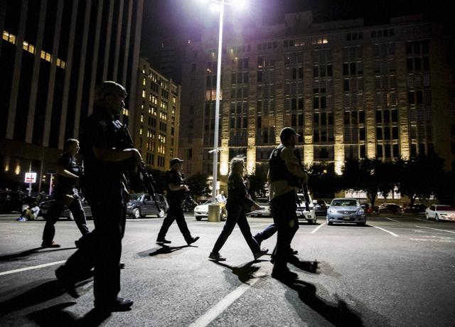 A woman is escorted to her car by armed officers in Dallas. (AP) A woman is escorted to her car by armed officers in Dallas. (AP)