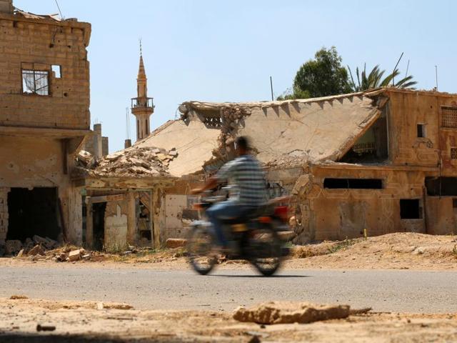 A man rides a motorbike past damaged buildings along a street in the rebel-held town of Dael, in Deraa Governorate, Syria.(REUTERS) A man rides a motorbike past damaged buildings along a street in the rebel-held town of Dael, in Deraa Governorate, Syria.(REUTERS)