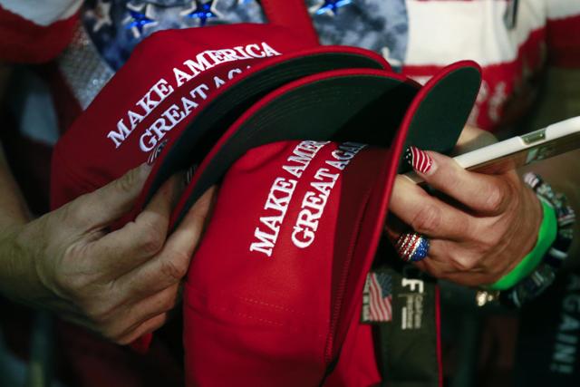 A woman holds hats to get them autographed by Republican presidential candidate Donald Trump during a rally in San Jose. (AP)