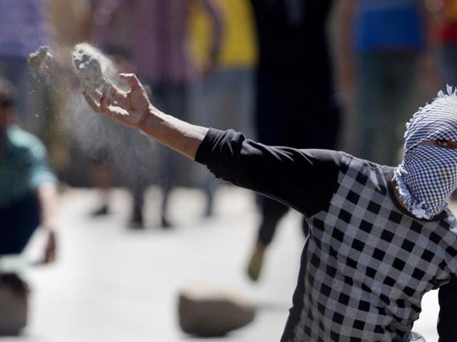 A protester throws a rock at policemen in Srinagar. Afspa, a law which gives security forces sweeping powers, was imposed in Kashmir in 1990.(AP)