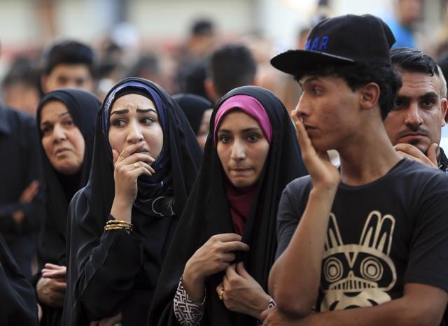People wait for family members who went missing as paramedics look for burned bodies inside a mall at the scene of Sunday's massive truck bomb attack claimed by the Islamic State group. (AP)