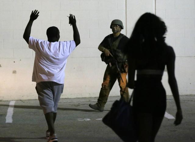 A man raises his hands as he walks near a law enforcement officer, following the shootings Thursday of several police officers in downtown Dallas. (AP) A man raises his hands as he walks near a law enforcement officer, following the shootings Thursday of several police officers in downtown Dallas. (AP)