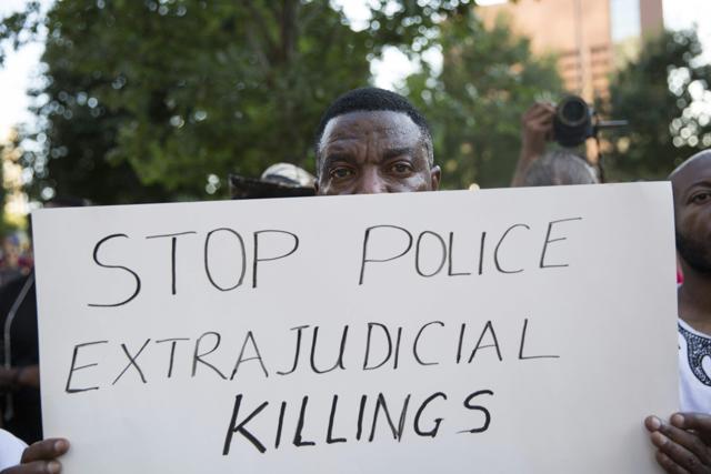People rally in Dallas, Texas, on Thursday, July 7, 2016 to protest the deaths of Alton Sterling and Philando Castile. Black motorist Philando Castile, 32, a school cafeteria worker, was shot at close range by a Minnesota cop and seen bleeding to death in a graphic video shot by his girlfriend that went viral Thursday, the second fatal police shooting to rock America in as many days. / AFP PHOTO / Laura Buckman (AFP)