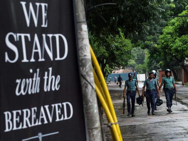 Bangladeshi policemen walk near a banner that reads "We stand with the bereaved" in a street near an upscale restaurant which was the site of a bloody siege that ended in the death of seventeen dead foreigners and five Bangladeshis, in Dhaka. (AFP Photo) Bangladeshi policemen walk near a banner that reads "We stand with the bereaved" in a street near an upscale restaurant which was the site of a bloody siege that ended in the death of seventeen dead foreigners and five Bangladeshis, in Dhaka. (AFP Photo)