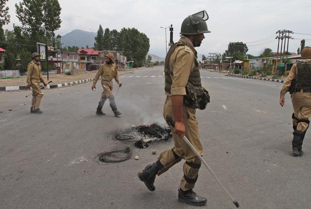 Policemen walk past burning tires set up as a road blockade during curfew in Srinagar. (AP Photo) Policemen walk past burning tires set up as a road blockade during curfew in Srinagar. (AP Photo)