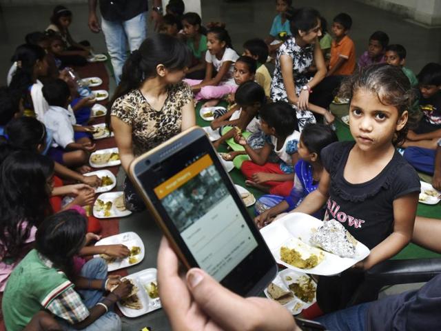 Kids eat lunch at a Noida temple, one of 80 hunger spots identified by No Food Waste on its app. The start-up receives donations of excess food and distributes these among the poor.(Raj K Raj/HT Photo)