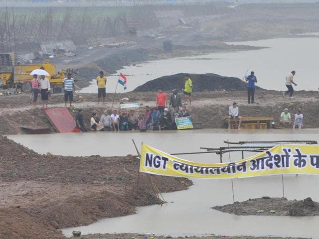People stand in the Pipliyahana reservoir to protest the decision to construct the court complex, in Indore on Sunday.(Shankar Mourya/HT photo)