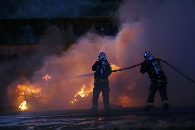 French firemen extinguish flames from burning vehicles near the Paris fan zone. (REUTERS)