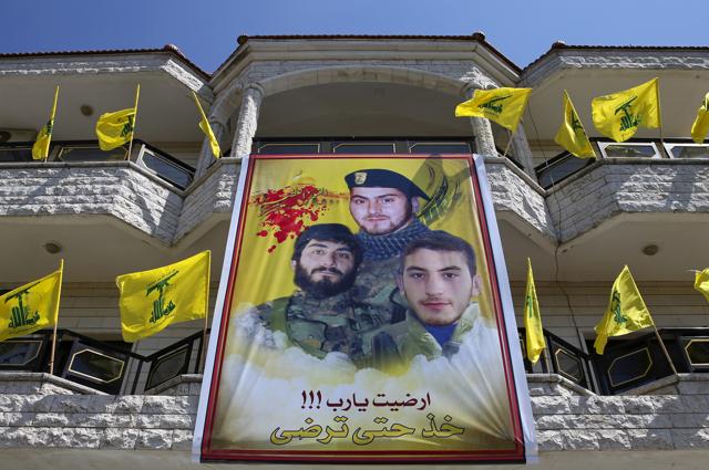 In this photo, a huge poster showing portraits of Mahdi Daqiq (top) who was killed in August 2006 and his nephew Mohammed Daqiq (right), who was killed in July 2006 during fighting with Israel in the 2006 war and his nephew Ali Daqiq who was killed in Khalsa, southern Aleppo, in June, 2016. Arabic on the poster reads "Is this enough, God!!! Take until you're satisfied." (AP) In this photo, a huge poster showing portraits of Mahdi Daqiq (top) who was killed in August 2006 and his nephew Mohammed Daqiq (right), who was killed in July 2006 during fighting with Israel in the 2006 war and his nephew Ali Daqiq who was killed in Khalsa, southern Aleppo, in June, 2016. Arabic on the poster reads "Is this enough, God!!! Take until you're satisfied." (AP)