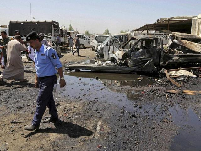 Civilians and security personnel gather at the scene of a deadly suicide car bombing at an outdoor market in a Shia-dominated al-Rashidiya district. (AP) Civilians and security personnel gather at the scene of a deadly suicide car bombing at an outdoor market in a Shia-dominated al-Rashidiya district. (AP)