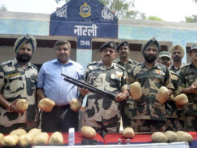 BSF officials display the shot gun, ammunition and 21 packets of contraband recovered near Narli village on Wednesday. (Sameer Sehgal/HT Photo)