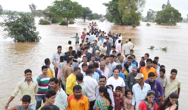 People wade through the water at Karver in Kolhapur. (ht photo)