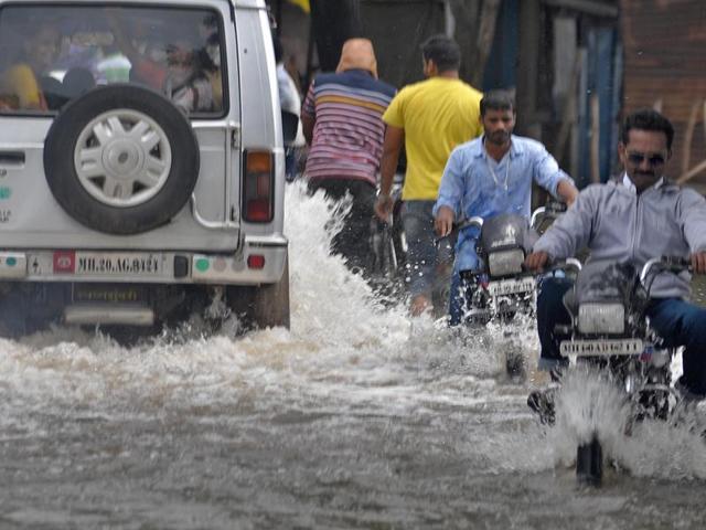 Local residents struggle through submerged roads in Sangli on Wednesday. (UDAY DEOLEKAR)