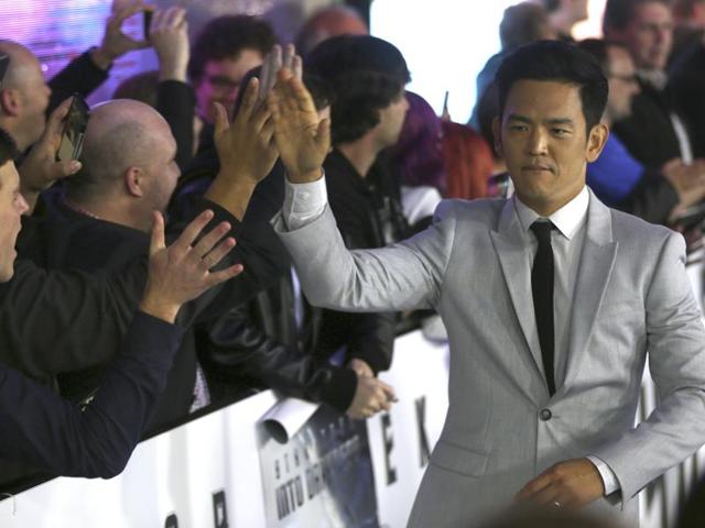 Actor John Cho, who plays Hikaru Sulu, hi-fives fans as he walks on the red carpet during the premiere of the film Star Trek Beyond. (AP) 