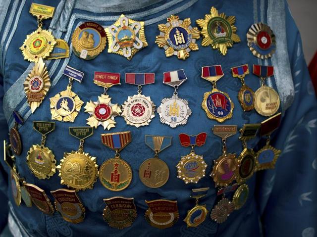 The nine white banners, a pole with circularly arranged horse or yak tail hairs representing the nine tribes of Mongolia, is still taken from Sukhbaatar Square, the main square in Ulaanbaatar, to the national stadium where the ceremony is held. Medals adorn the dress of a woman in traditional Mongolian clothing. (AP) The nine white banners, a pole with circularly arranged horse or yak tail hairs representing the nine tribes of Mongolia, is still taken from Sukhbaatar Square, the main square in Ulaanbaatar, to the national stadium where the ceremony is held. Medals adorn the dress of a woman in traditional Mongolian clothing. (AP)