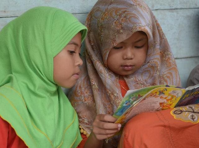 Seen here, two girls deeply engrossed in reading a book. (AFP) 