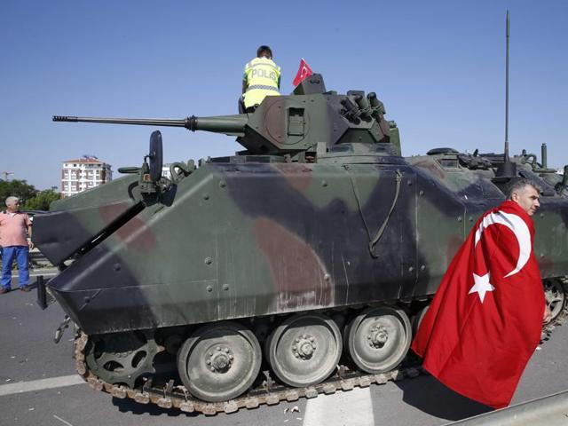 A man wrapped in a Turkish flag walks past a military vehicle in front of Sabiha Airport, in Istanbul, Turkey. (Reuters Photo) A man wrapped in a Turkish flag walks past a military vehicle in front of Sabiha Airport, in Istanbul, Turkey. (Reuters Photo)