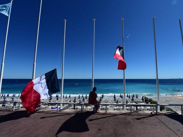 A woman sits under French flags lowered at half-mast in Nice, following the deadly Bastille Day attack. (AFP Photo) A woman sits under French flags lowered at half-mast in Nice, following the deadly Bastille Day attack. (AFP Photo)