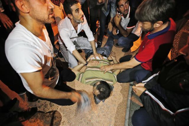 People protesting against the coup, attend to a man, wounded when Turkish forces soldiers opened fire to disperse the crowd in Istanbul's Taksim square, early Saturday. (AP Photo)