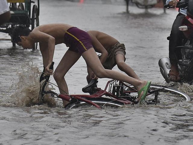 Boys struggle to make their way through a waterlogged street on their bicycles. (Raj K Raj/HT Photo) Boys struggle to make their way through a waterlogged street on their bicycles. (Raj K Raj/HT Photo)