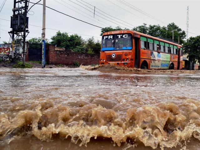A bus sends ripples across a waterlogged national highway in Jalandhar following heavy rains on Sunday. (PTI) A bus sends ripples across a waterlogged national highway in Jalandhar following heavy rains on Sunday. (PTI)