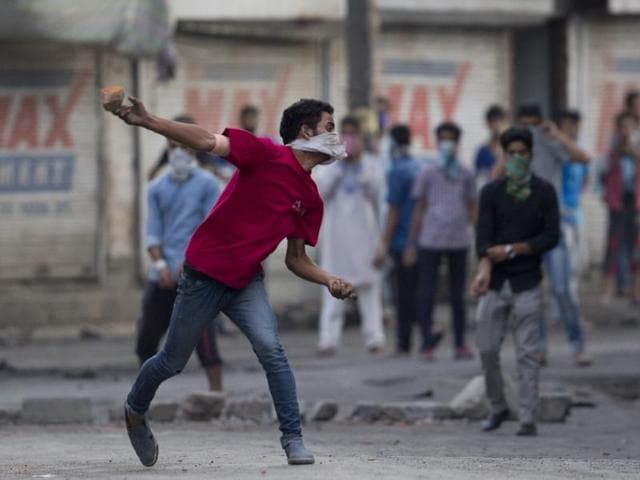 A masked Kashmiri protester throws bricks at Indian security men during a protest in Srinagar.(AP)