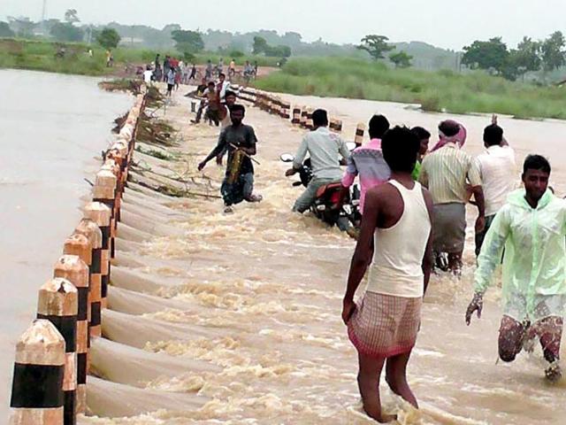 Villagers in West Bengal’s Birbhum cross a bridge submerged due to heavy rain, on Saturday. (PTI) Villagers in West Bengal’s Birbhum cross a bridge submerged due to heavy rain, on Saturday. (PTI)