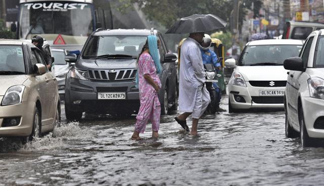 People cross a waterlogged road in eastern Delhi on Saturday. (Raj K Raj/ HT Photo ) People cross a waterlogged road in eastern Delhi on Saturday. (Raj K Raj/ HT Photo )