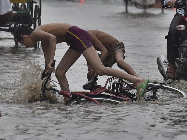 Two boys riding a cycle trip on a flooded Delhi road. (Raj K raj/ HT photo) Two boys riding a cycle trip on a flooded Delhi road. (Raj K raj/ HT photo)