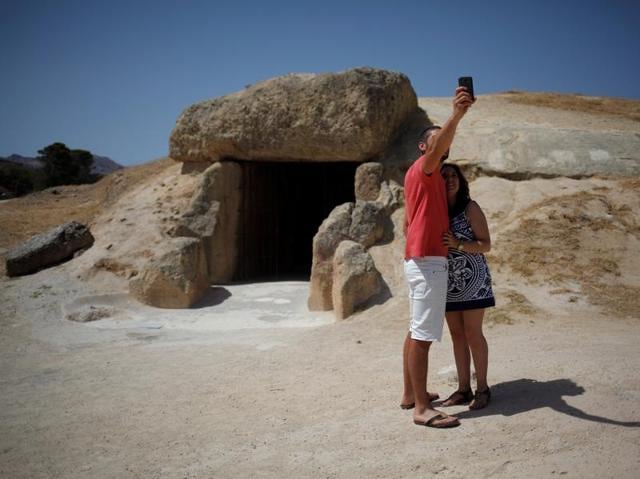 A dolmen is a megalithic (prehistoric) tomb with a large flat stone laid on upright ones. A couple takes a selfie outside the Menga dolmen. (REUTERS)