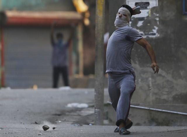 A masked Kashmiri protester throws stones at policemen as they clash in Srinagar. (AP) A masked Kashmiri protester throws stones at policemen as they clash in Srinagar. (AP)