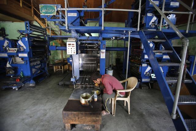 Mohammad Ishaq, an employee of the Daily Kashmir Images, has his lunch in front of printing machines on the outskirts of Srinagar. (AP) Mohammad Ishaq, an employee of the Daily Kashmir Images, has his lunch in front of printing machines on the outskirts of Srinagar. (AP)