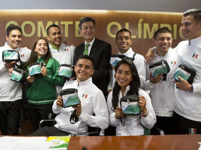 Pablo Kuri Morales poses with athletes from Mexico's Olympic delegation as they hold health kits. (AP Photo)