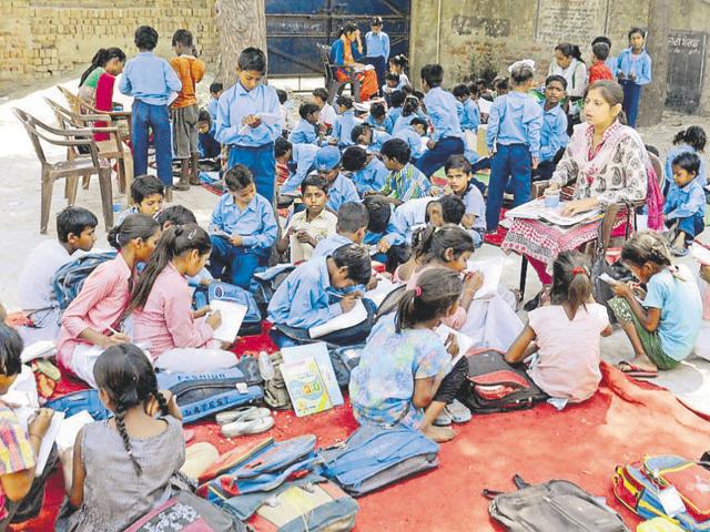 Students sitting on mats in the open in absence of a building.(Sameer Sehgal/HT Photo)