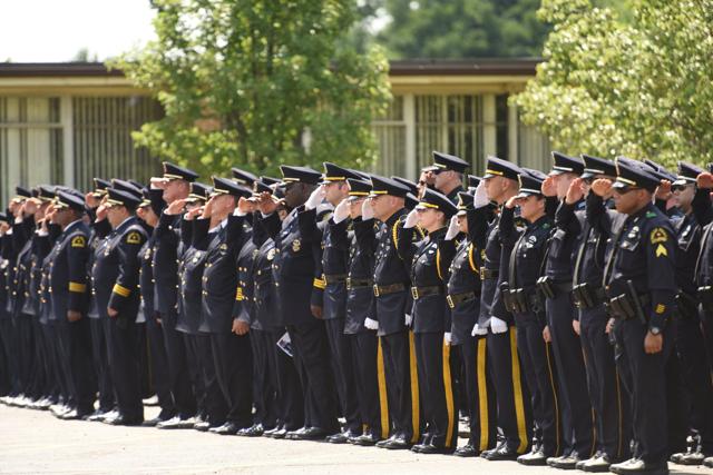 Law enforcement officers salute during the funeral service for slain officer Michael Krol in Redford Township. (AP Photo)