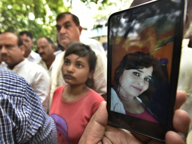 Soni Mishra’s family show her photo on a phone as they wait outside the Lok Nayak hospital mortuary.(Raj K Raj/HT Photo)