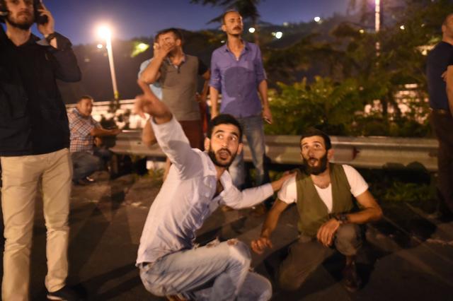 People take cover as jet fighters pass over near the Bosphorus bridge as Turkish military clash with people at the entrance to the bridge in Istanbul on July 16, 2016. (Bulent Kilic / AFP)