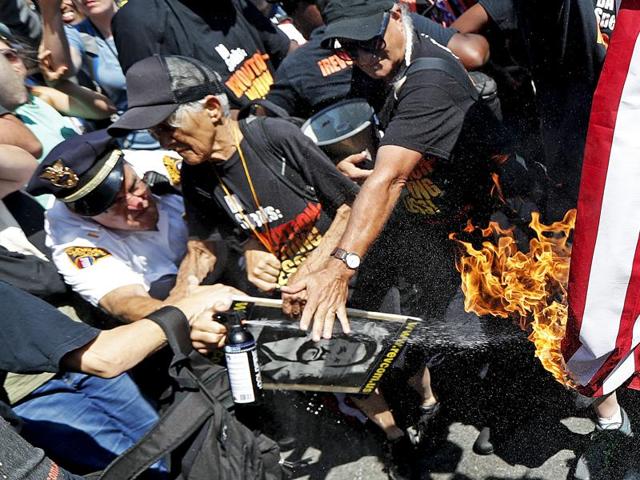 A law enforcement officer tries extinguish a burning American flag on Wednesday in Cleveland, during the third day of the Republican convention. (AP) A law enforcement officer tries extinguish a burning American flag on Wednesday in Cleveland, during the third day of the Republican convention. (AP)