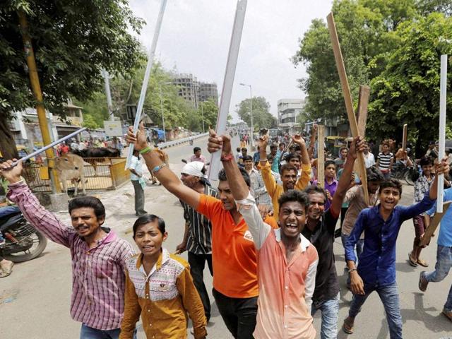 Dalit youths hold wooden sticks and shout slogans in Ahmedabad on Wednesday to protest the violence against four men from Dalit community for trying to skin a dead cow in Una town in Gujarat last week.(PTI)