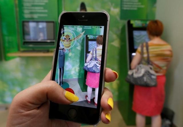 A woman plays the augmented reality mobile game "Pokemon Go" by Nintendo, as a visitor uses an automated teller machine (ATM) at a branch of Sberbank in central Krasnoyarsk, Siberia, Russia. (Reuters Photo) A woman plays the augmented reality mobile game "Pokemon Go" by Nintendo, as a visitor uses an automated teller machine (ATM) at a branch of Sberbank in central Krasnoyarsk, Siberia, Russia. (Reuters Photo)