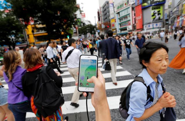 A man plays the augmented reality mobile game by Nintendo on his mobile phone as he walks at a busy crossing in Shibuya district in Tokyo, Japan, on July 22, 2016. (REUTERS)