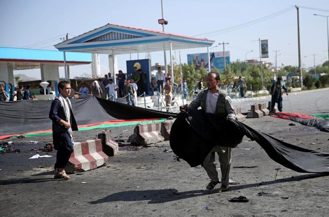 An Afghan man uses a banner in the colours of the Afghan flag to cover victims blood, after a deadly explosion struck a protest march by ethnic Hazaras. (AP) An Afghan man uses a banner in the colours of the Afghan flag to cover victims blood, after a deadly explosion struck a protest march by ethnic Hazaras. (AP)