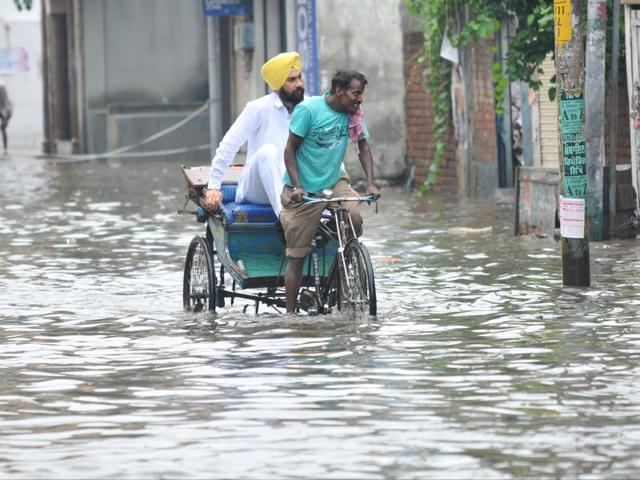 A rickshaw puller paddling through the waterlogged road in Jalandhar on Saturday. (Pardeep Pandit/HT Photo) 