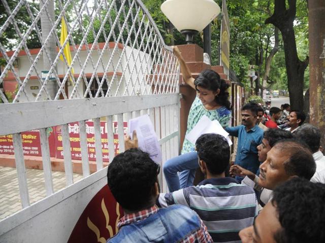 A girl student tries to jump over the fence of the examination centre after being denied entry for being late in Lucknow on Sunday. (Deepak Gupta/ HT photo)